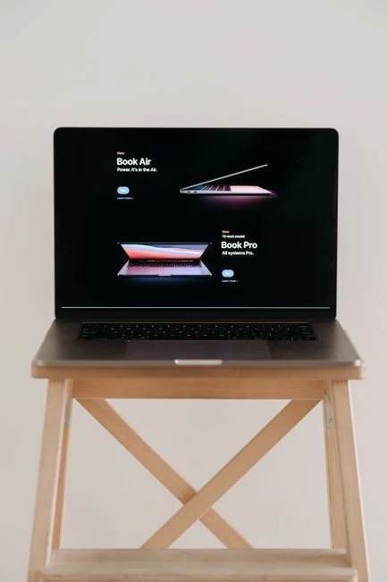 Close-up of hands typing on a laptop next to a cup of coffee on a wooden desk.